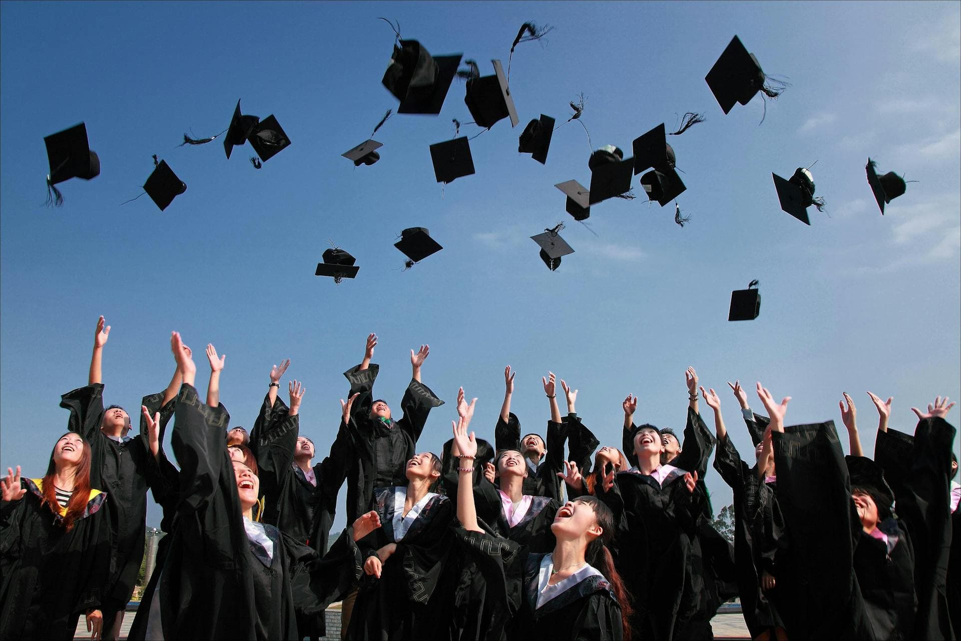 College graduates celebrating by throwing caps in the air at commencement ceremony for the Marc Zboch Academic Scholarship